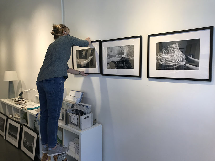 Martha Spak Hanging Photos in a Gallery.